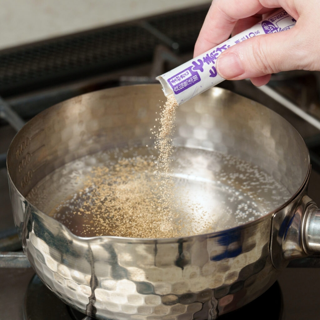 Dashi powder being added to a pot.