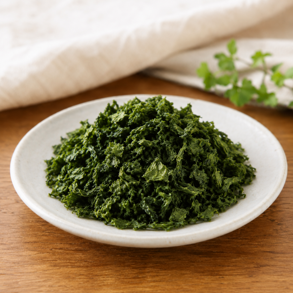 Dried aosa seaweed in a small ceramic dish on a wooden table.