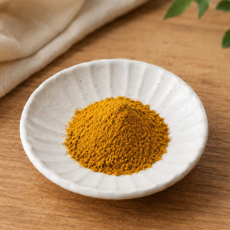 Golden yellow curry powder served in a small white ceramic dish on a wooden table.