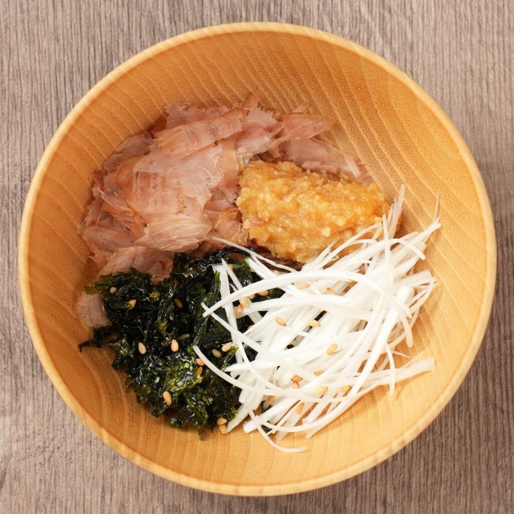 Kachuyu ingredients in a wooden bowl with bonito flakes, miso, Korean roasted seaweed, Japanese leek, and sesame seeds.