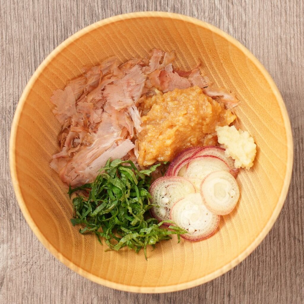 Kachuyu ingredients in a wooden bowl with bonito flakes, miso, myoga, shiso, and grated ginger.