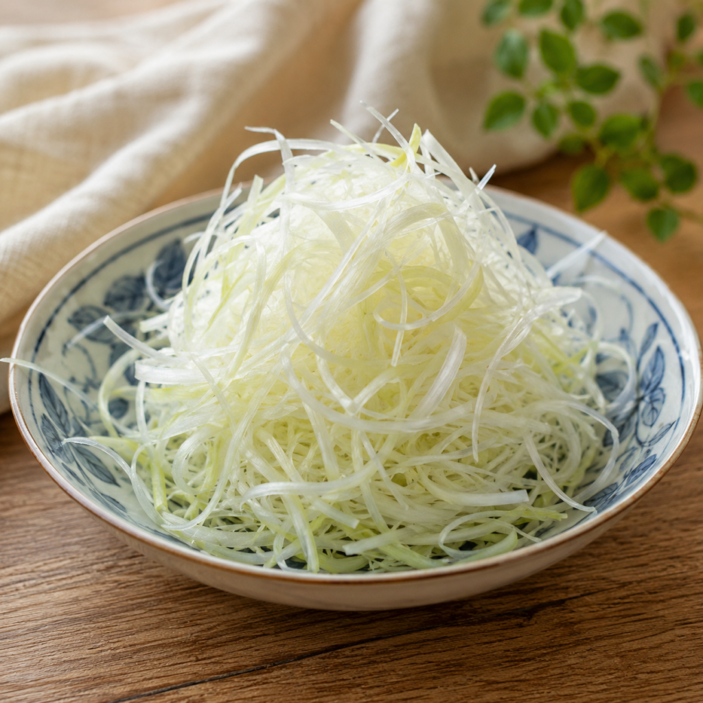 Shiraga negi, finely shredded Japanese leek, in a painted ceramic dish.