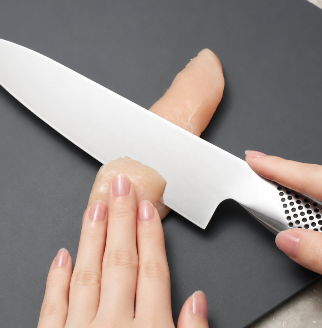 Chicken tenderloin being cut into thin diagonal slices using the sogigiri technique