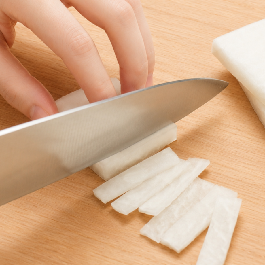 Daikon being cut into thin rectangular slices using the tanzakugiri technique