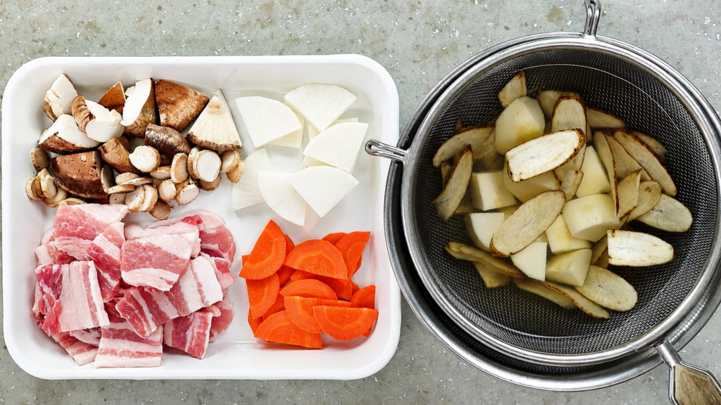 Prepared ingredients for tonjiru, including pork belly, daikon, carrot, burdock root, taro, and shiitake mushrooms.