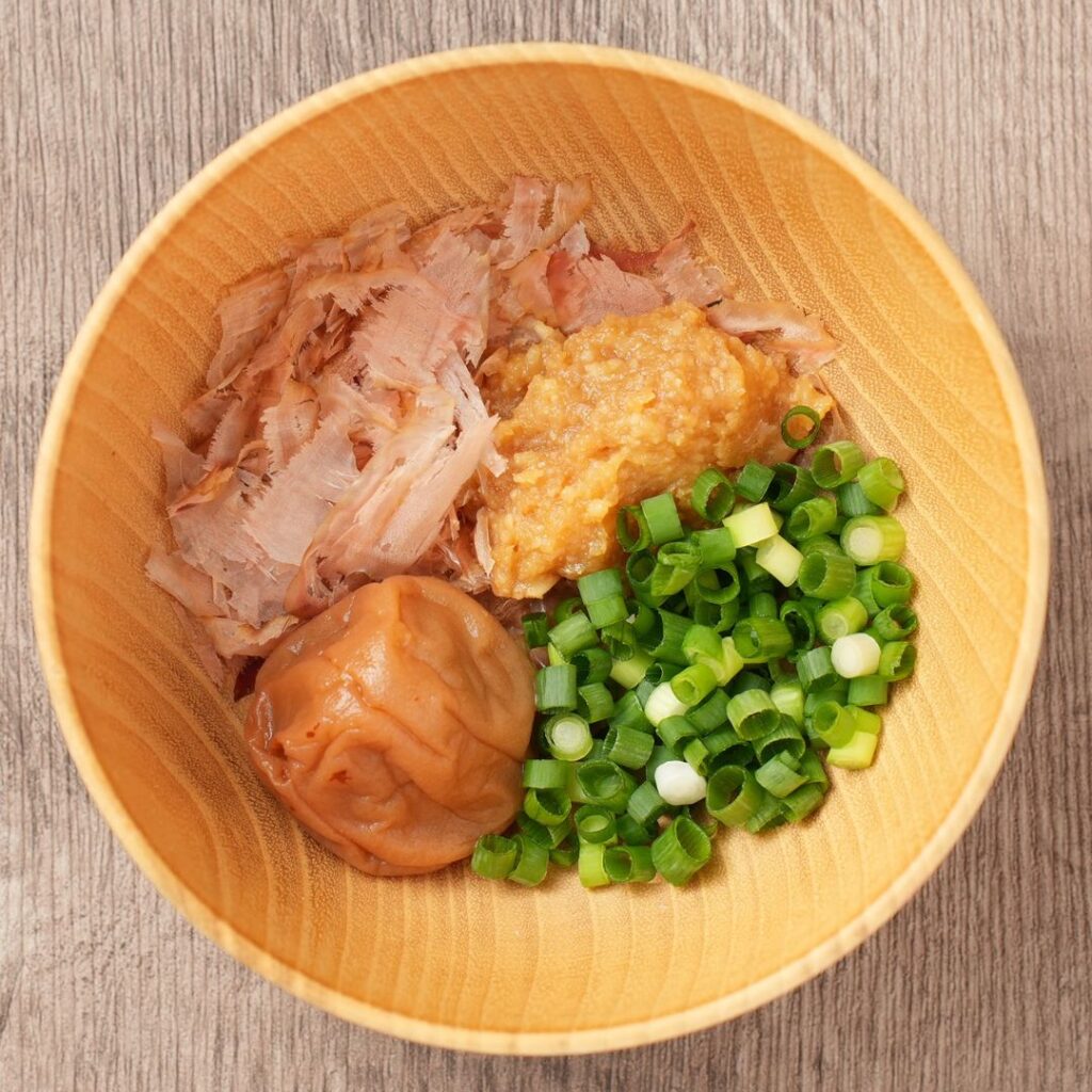 Kachuyu ingredients in a wooden bowl with bonito flakes, miso, umeboshi, and chopped green onion.