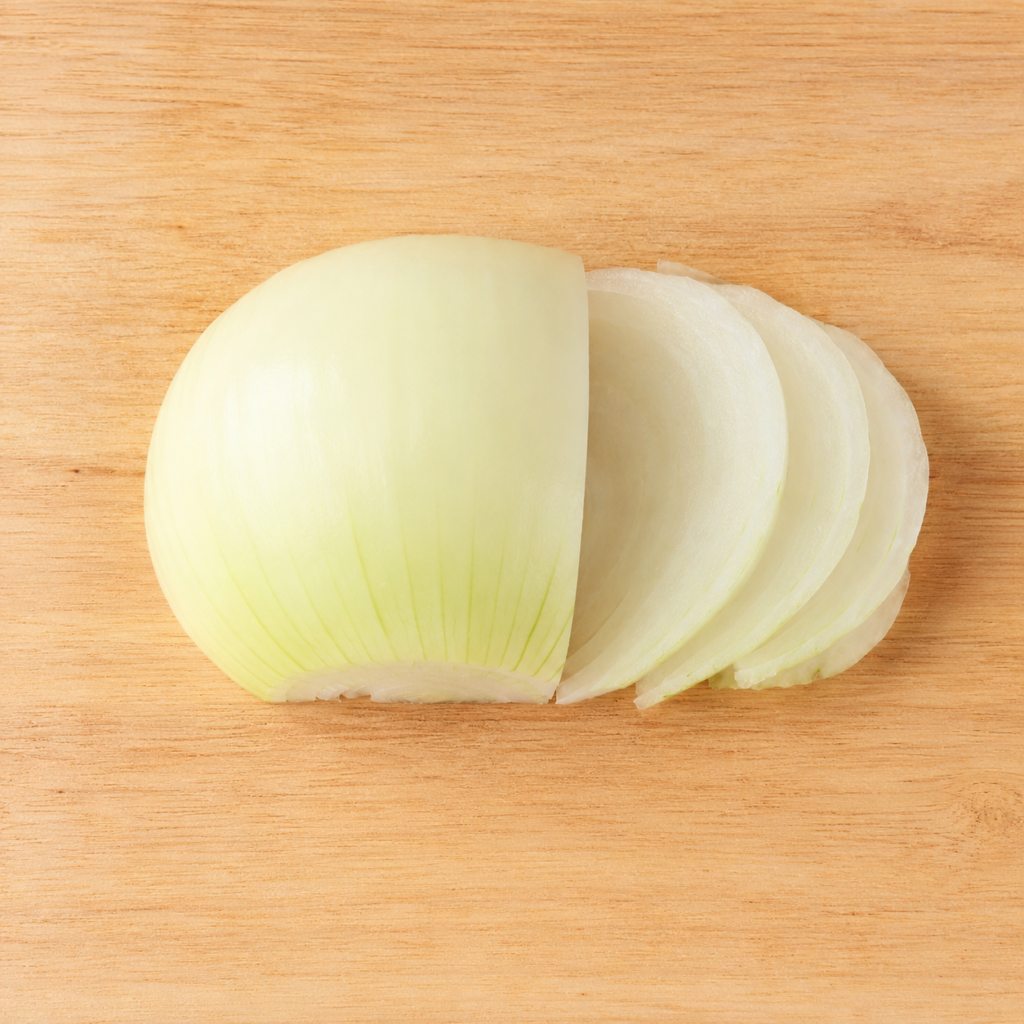 Yellow onion thinly sliced along the grain on a wooden cutting board