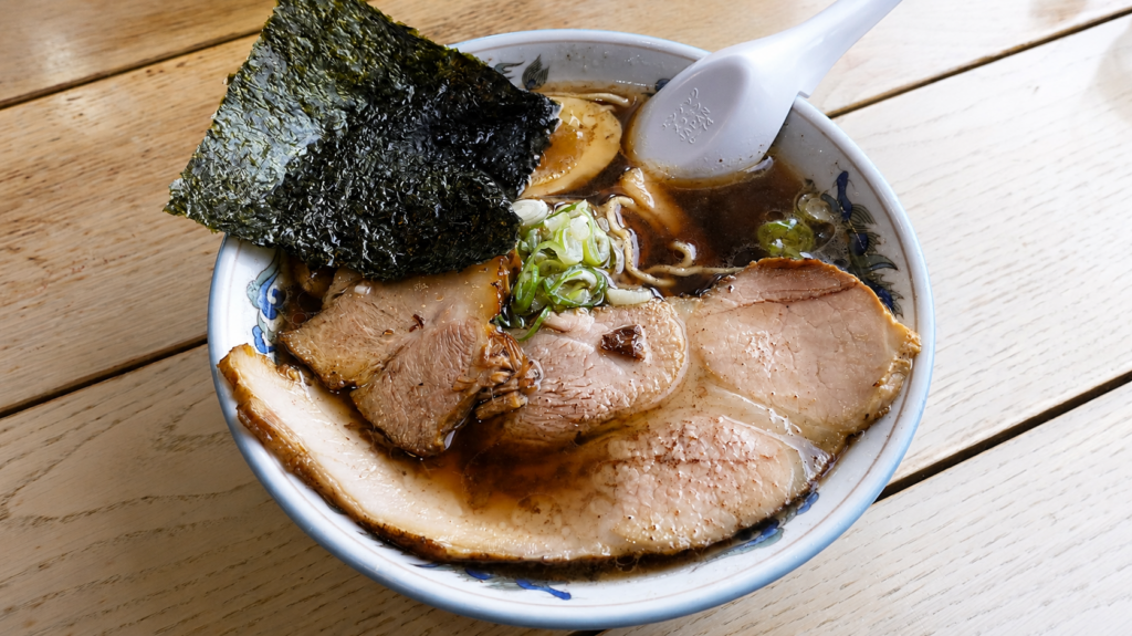 Kuroshio Ramen at Oshokujidokoro Satsuki in Kamikawa, Hokkaido, topped with chashu pork, nori, green onions, and half a soft-boiled egg.