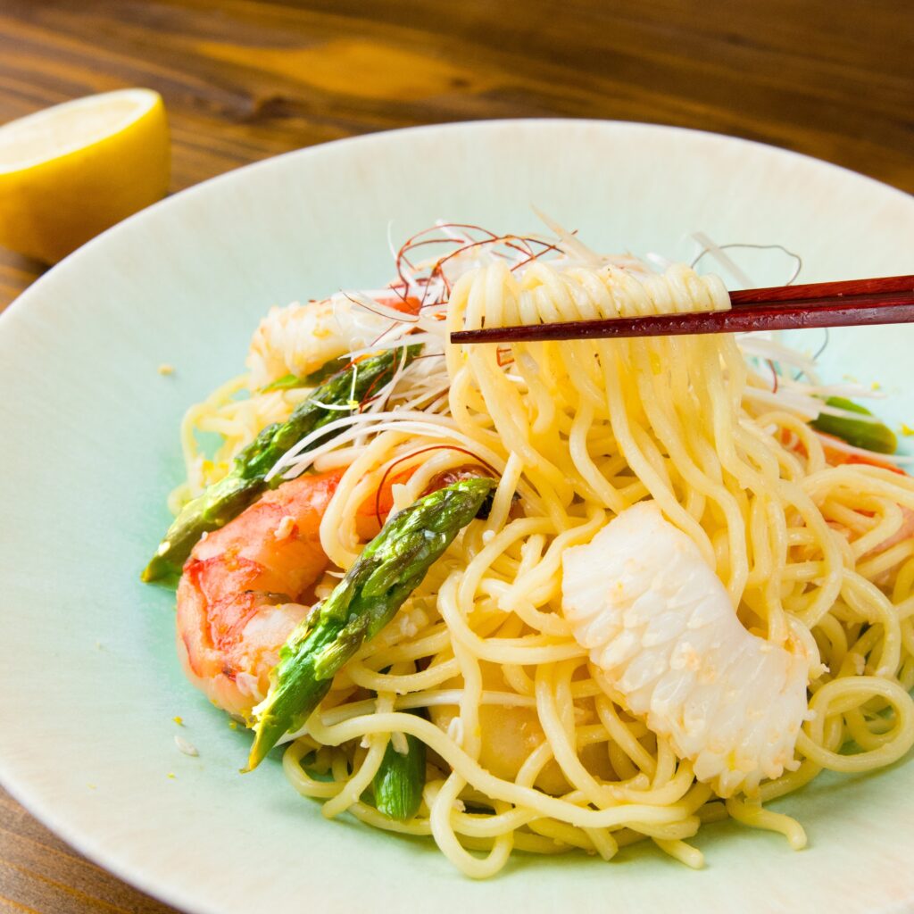 Seafood yakisoba with shrimp, scallop, squid, asparagus, white leek garnish, and lemon
