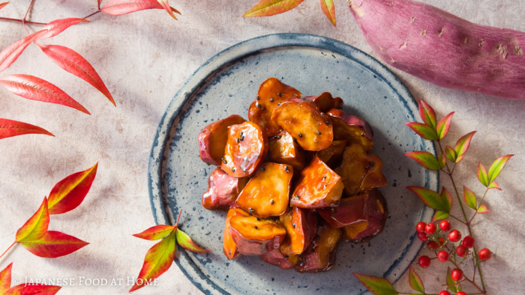 Daigaku imo, Japanese candied sweet potatoes served on a blue plate with autumn leaves and a whole sweet potato