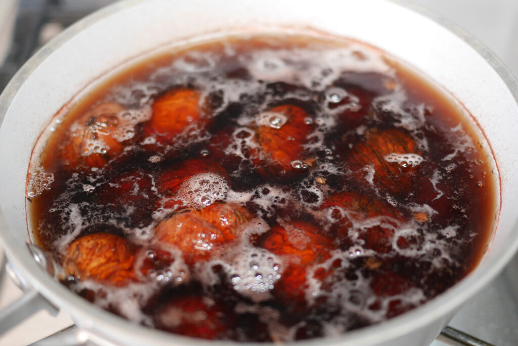 Chestnuts simmering with baking soda as the cooking water turns dark brown