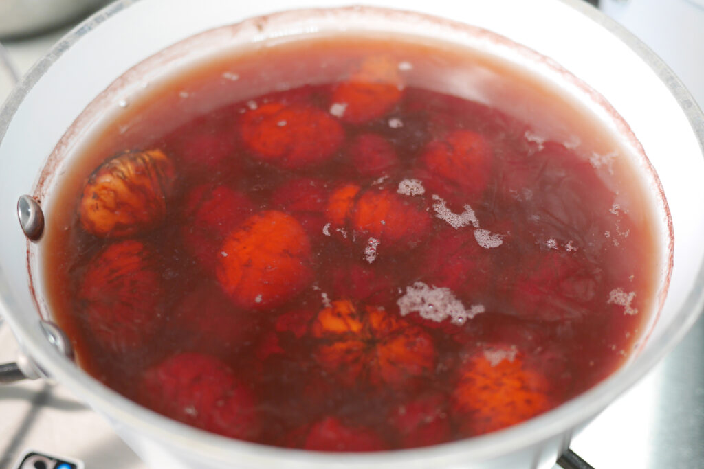 Chestnuts simmering in light reddish-brown water after repeated rinsing and boiling